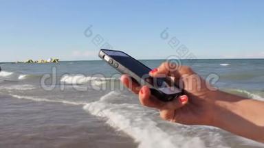 穿比基尼的女人在海滩上用智能手机发短信。 户外使用智能手机特写双手。 移动